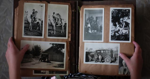 Persoon bladert door een fotoalbum met oude foto's op zoek naar familiegeschiedenis.