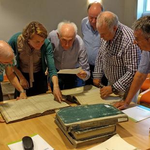 Hulgroepen en cursussen: erfgoedvrijwilligers buigen zich over enkele historische documenten.