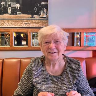 Foto van Lieve Van der Velden in een cafeetje. Op de achtergrond een leren bank en kleine spiegeltjes.