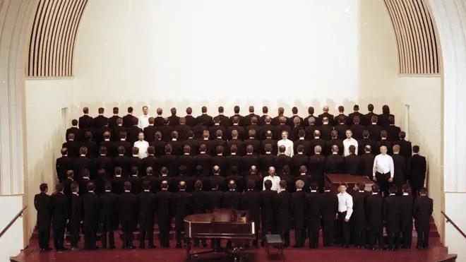 Het San Francisco gay men’s chorus in 1993, na twaalf jaar aidscrisis. De zeven mannen in het wit zijn de leden die overleven. De 115 mannen in het zwart representeren de koorleden die aan aids overleden zijn.